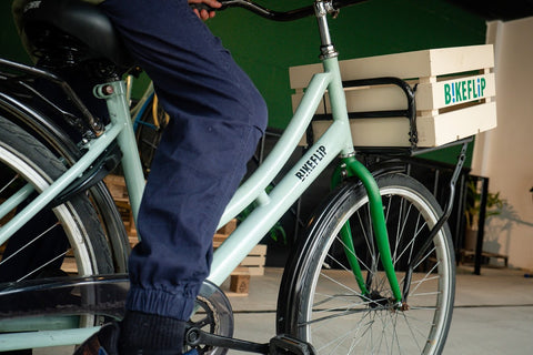 Een close-up van een groene fiets en een persoon die erop zit en gestopt is. - BikeFlip