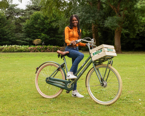 Blij meisje rijdt op een groene fiets in het park. - BikeFlip